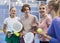 Smiling young man and women with padel rackets posing at court inside