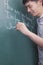 Smiling young man writing English sentences on the blackboard