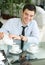 Smiling young men pours tea into a cup.