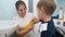 Smiling young mother helping little son putting on yellow rubber gloves before doing housework in bathroom. Children