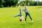 smiling young mother looking at daughter performing handstand on green meadow