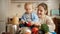 SMiling young mother showing broccoli to her baby son while cooking on kitchen. Concept of little chef, children cooking food,