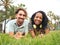 Smiling young multiethnic heterosexual couple lying on the grass in a park