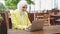 Smiling young muslim woman wearing headscarf sits in cafe and uses laptop
