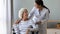 Smiling young nurse taking care of happy handicapped older patient.