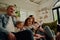 Smiling young parents sitting together with daughter controlling remote control at home