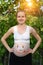 Smiling young pregnant woman with a painted smiling face on her belly. Green background