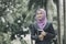 Smiling young professional muslimah businesswoman holding a tablet in the park