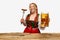 Smiling young redhead woman dressed traditional dirndl, holding huge juicy,appertizing Bavarian sousage and beer mug