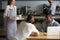 Smiling young waitress serve coffee to male cafe visitors