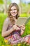 Smiling Young Winsome Caucasian Blond Woman Reading Paper Book Outdoor While Sitting Against Green Grass