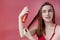 Smiling young woman applying oil mask to hair tips, haircare concept