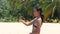 A smiling young woman in bikini filming videos at the beach on a hot summer day.