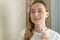 Smiling young woman with braces cleaning her teeth with water irrigator