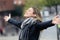 Smiling young woman breathing fresh air and raising arms in the city.