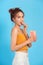 Smiling young woman in casual summer clothes, hold bucket of popcorn isolated on blue background