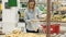 Smiling young woman choosing potatoes in grocery store