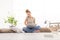 smiling young woman with computer talk on the cell phone, sitting on the floor in living room on white wide window in