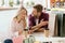 smiling young woman counting cash money after shopping while her upset boyfriend