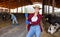 Smiling young woman cow breeder standing in cowshed