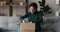 Smiling young woman customer opening parcel box seated on couch