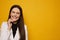 Smiling young woman in dental braces posing with closed eyes at the yellow background, isolated. Latino brunette closing