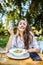 Smiling young woman enjoys fresh vegetable salad at cafe, has lunch after work, keeps to diet, eats only healthy food, being satis