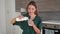 Smiling young woman fills glass of kefir in the kitchen of her home