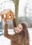 Smiling young woman hanging bird feeder on tree