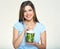 Smiling young woman holding blender with green smoothy ingredients.