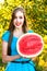 Smiling young woman holding half of juicy watermelon