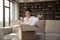 Smiling young woman holds cellphone while unpack received parcel box