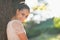 Smiling young woman lean against tree