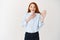 Smiling young woman looking with excitement while making promise, raising one hand and giving oath, standing over white