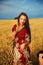 Smiling Young woman with ornamental dress standing on a wheat field with sunset. And photographer hand with camera..