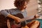 Smiling young woman playing guitar at home