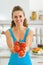 Smiling young woman showing bunch of tomato in modern kitchen