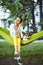 Smiling young woman sitting in green hammock with cute dog Welsh Corgi in a park outdoors. Beautiful happy female in