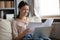 Smiling young woman sitting on sofa, reading paper letters.