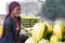 Smiling young woman standing between fruit shelves.