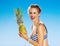 Smiling young woman in swimwear on seacoast with pineapple