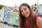 Smiling young woman tourist taking selfie self portrait sitting on the bench decorated with mosaic in famous Park Guell, Barcelona