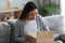 Smiling young woman unpacking parcel, opening cardboard box