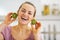 Smiling young woman using kiwi slices as earrings