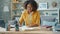 Smiling young woman writing in notebook at desk at home working at project