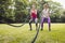 Smiling young women doing battle rope exercise in park