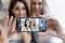 Smiling young women friends, brunette and blonde, make selfie on the phone in a cafe. Friendship and communication