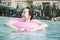 Smiling young women in the pool with an inflatable tube, looking away