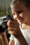 Smiling youthful girl with photocamera looking through new photos