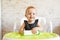 Smilling baby holding bottle of milk in sunny modern kitchen, nutrition dinner for kids